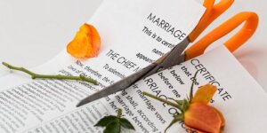 Scissors cut a marriage certificate and orange rose in half