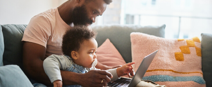 Father with baby on his lap working on a computer