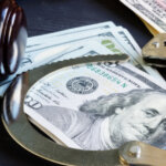 Image of hundred dollar bills, handcuffs, and a legal gavel